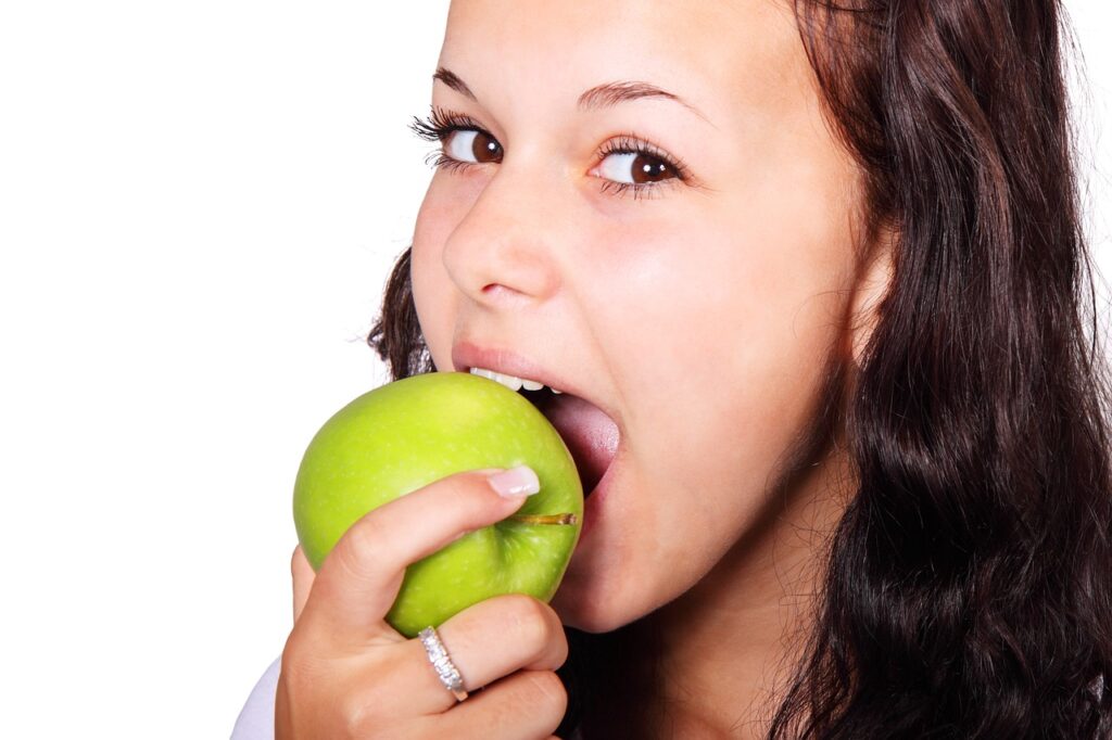 junge Frau isst einen Apfel Zunehmen auf gesunde Weise Tipps zur Ernährung